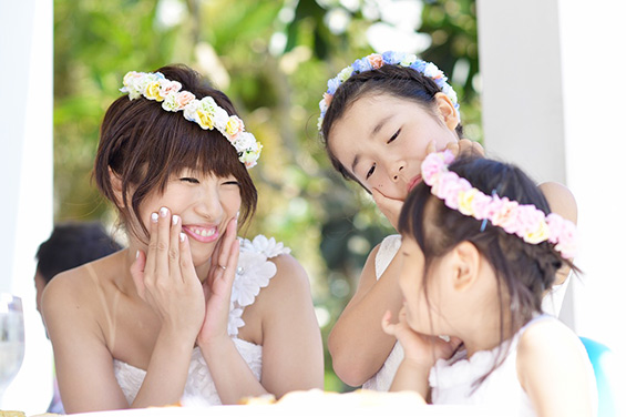 花嫁と一緒に花飾りをして笑う子供たちの写真